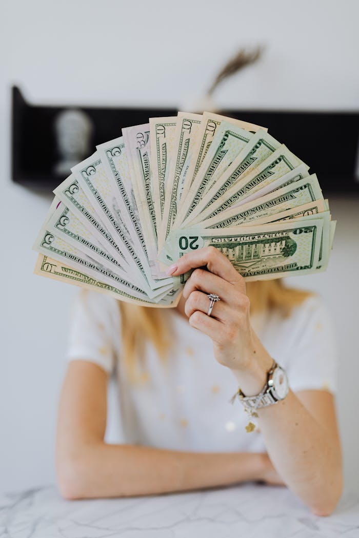 A person holding a fan of US dollar bills, symbolizing wealth and financial success.